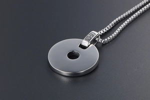 Détail macro du pendentif rond en acier inoxydable poli avec chaîne box et bélière