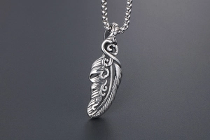 Detailed close-up of retro stainless steel feather pendant with intricate carvings