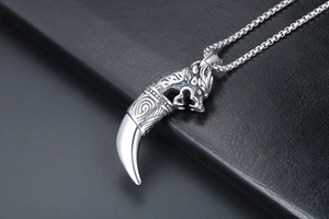 Detail of vintage punk wolf head pendant with sharp tooth on black leather surface