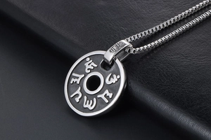 Gros plan du pendentif circulaire en acier inoxydable avec mantra gravé sur cuir noir