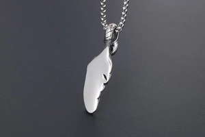 Detailed close-up of a silver wing pendant with polished finish on a box chain necklace