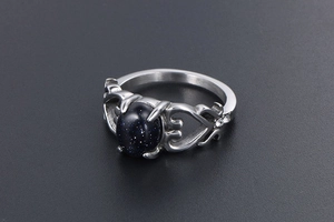 Dettaglio dell'anello vintage con cuori traforati, pietra blu e piccoli punti luce