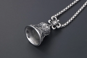 Macro shot of antique silver bell pendant with cross-line patterns and box chain