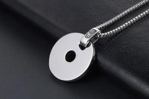 Vue macro d'un pendentif en titane argenté avec gravure fine sur fond de cuir