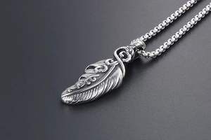 Detailed macro view of vintage silver feather pendant with textured wings and box chain