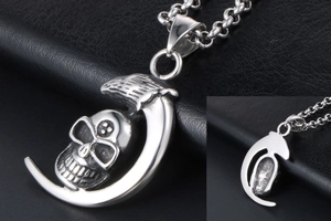 Macro view of vintage silver skull crescent moon pendant with gothic feather detail