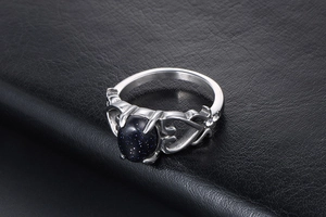 Dettaglio anello vintage a cuore con una grande pietra blu ovale in oro sintetico