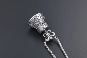 Macro view of vintage bell pendant with fleur-de-lis engraving and aged metal finish