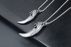 Close-up of retro wolf tooth pendants with intricate tribal engravings on dark leather