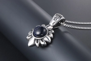 Détail du pendentif fleur en titane vintage avec pierre bleue et bélière gravée couronne