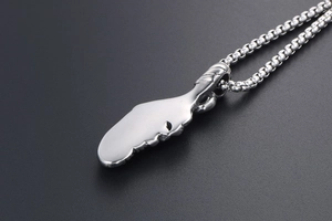 Macro shot of polished stainless steel wing pendant with cuban chain on black background