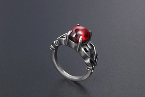 Dettaglio anello vintage con gemma ovale rosso scuro e fascia metallica traforata