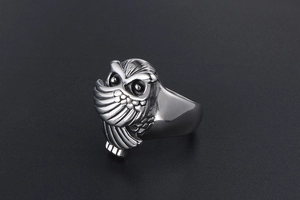 Détail macro d'une bague hibou rétro en acier titane avec texture gravée et style punk
