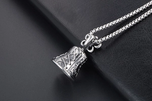 Close-up of vintage bell pendant with corset texture and box chain on black leather