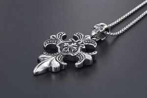 Détail d'un pendentif croix en titane vintage avec bélière tête de mort et lys