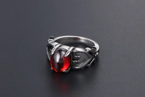 Dettaglio anello gotico in acciaio con gemma rossa ovale e design a cuore intagliato
