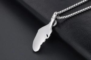 Macro view of a polished silver feather pendant with a smooth mirror finish on a box chain