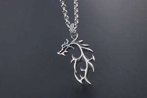 Vue détaillée du pendentif dragon argenté aux lignes tribales sur une chaîne épaisse