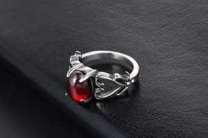 Dettaglio anello vintage a cuore con gemma rossa grande e motivi laterali traforati