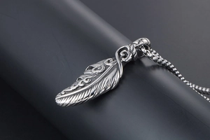 Detailed macro view of feather pendant crafted in polished titanium steel with ball chain