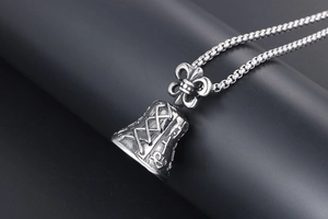 Macro detail of retro silver bell pendant with fleur-de-lis relief and box chain link