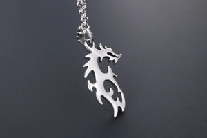 Gros plan d'un pendentif dragon en argent ajouré avec une chaîne à billes en acier
