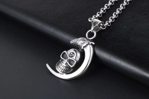 Close-up of punk style crescent moon and skull pendant necklace on black leather