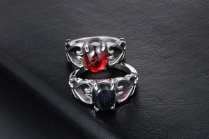 Dettaglio di anelli vintage a cuore con gemme ovali rosse e blu su fondo in pelle