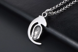Close-up of textured moon skull pendant with polished steel frame on black leather
