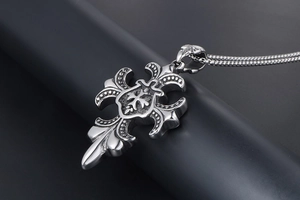 Détail macro du pendentif croix gothique en acier inoxydable avec fleur de lys et chaîne