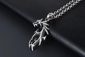 Détail d'un pendentif dragon en acier avec finition métallique sur cuir noir texturé
