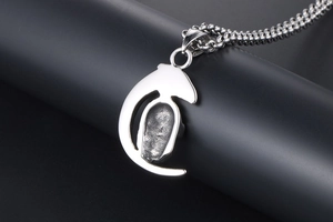 Close-up of crescent moon skull pendant in silver titanium steel on black pillar