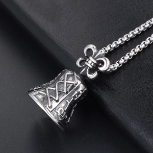 Vintage oxidized silver bell pendant necklace with fleur-de-lis detail on leather background