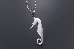 Detailed macro view of retro seahorse pendant with engraved bail on bead chain necklace
