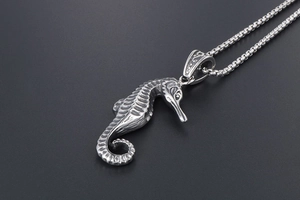 Macro detail of vintage silver seahorse pendant with textured steel box chain