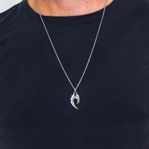 Gros plan d'un collier pour homme avec pendentif flamme sur fond de tissu noir