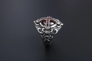 Macro detail of Gothic cross ring with red ruby gemstone and silver oxidized steel finish