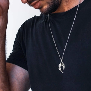 Gros plan d'un collier pendentif griffe tribal argenté sur un mannequin homme style urbain