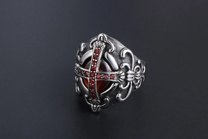 Macro detail of gothic cross ring with red gemstone and ornate medieval carvings