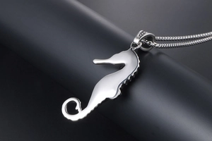 Detailed close-up of a vintage seahorse pendant with a sleek box chain on a black stand