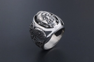 Gros plan du relief de Bouddha et des textures florales sur la bague vintage en acier