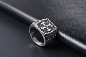 Makroaufnahme von Vintage-Ring aus Titanstahl mit geprägtem Kreuz auf schwarzem Lederhintergrund
