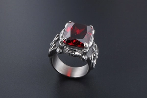 Close-up of gothic men's titanium steel ring with square red gemstone and relief carvings