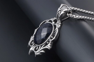 Macro view of teardrop blue sandstone pendant with vintage scrollwork on silver steel