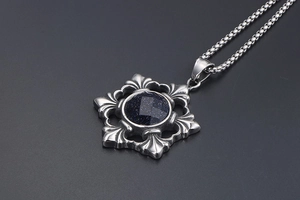 Detailed macro of vintage silver pendant with blue sandstone and gothic fleur-de-lis patterns