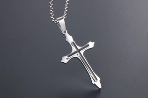 Macro view of polished silver cross pendant with black inlay on a round box chain