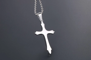 Detailed close-up of polished silver titanium steel cross pendant on a thin square pearl chain