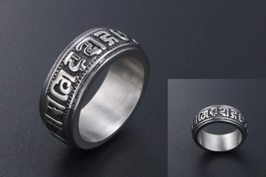 Detail of vintage titanium steel ring showing embossed Buddhist mantras and antique finish
