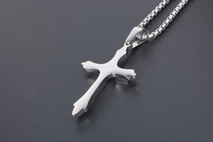 Macro view of silver cross pendant with durable box chain in polished stainless steel
