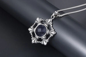 Macro shot of Gothic silver pendant with faceted blue sandstone on a gray stand